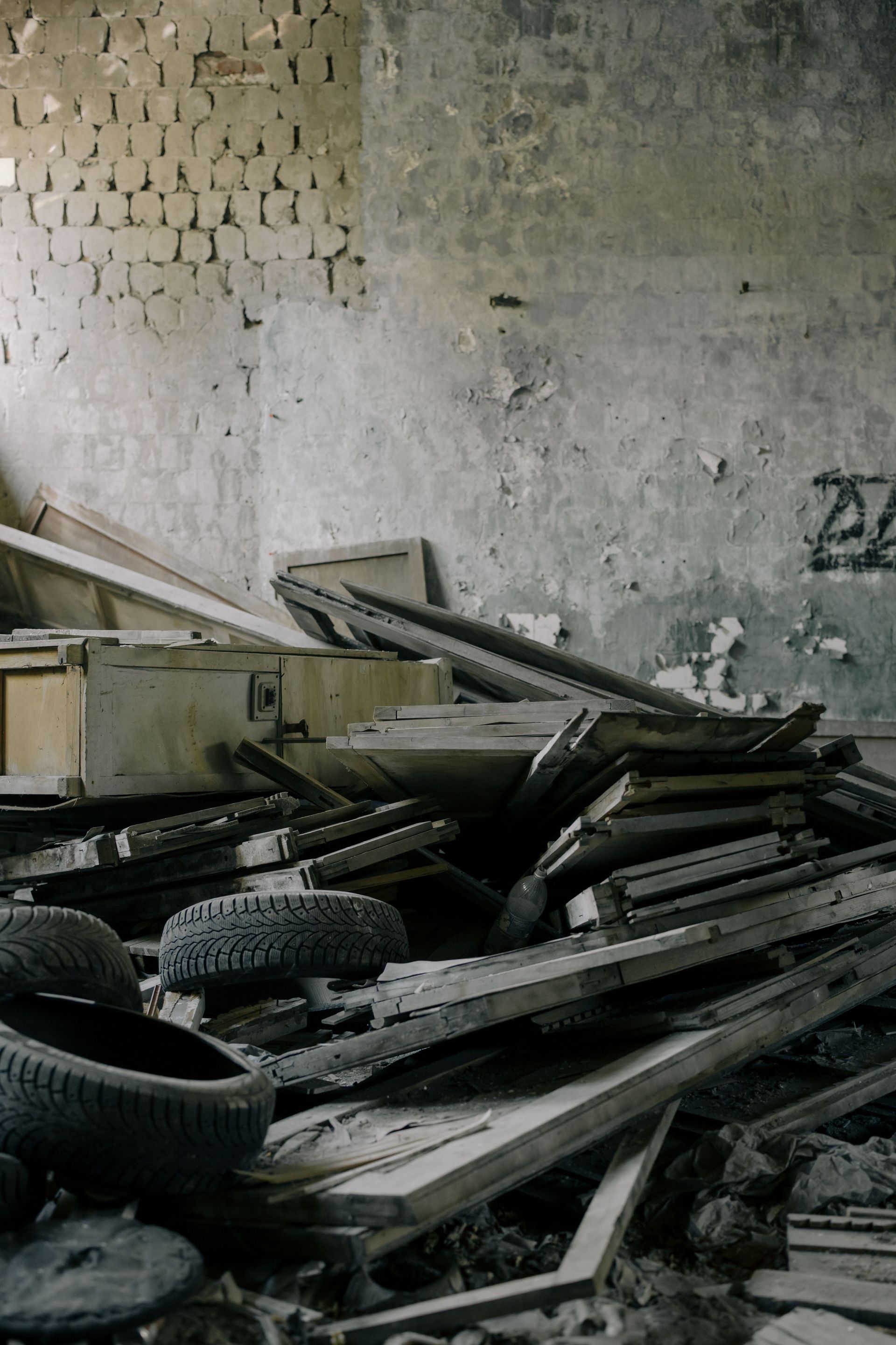 A cluttered abandoned room with broken furniture and old tires, symbolizing neglect and decay.